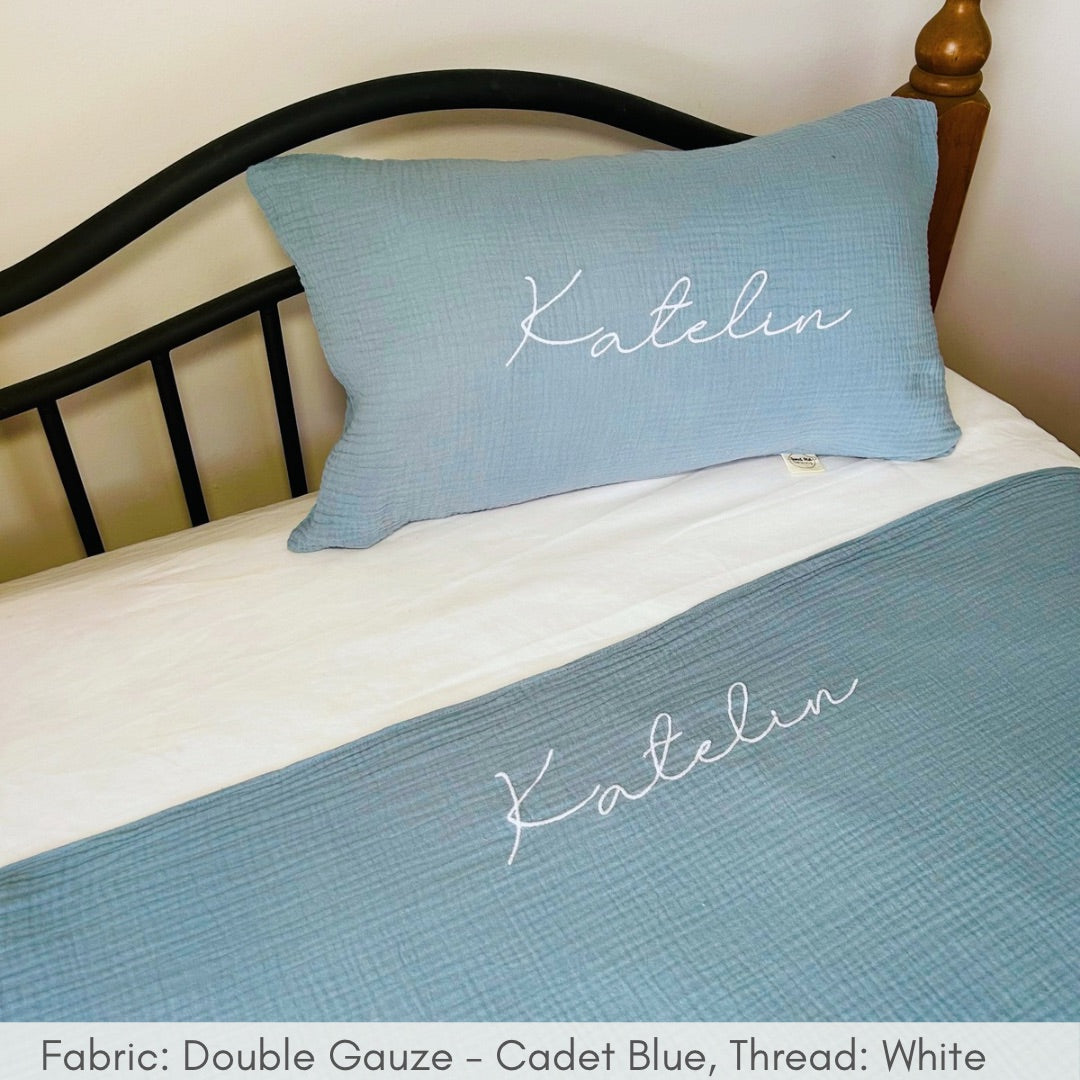 Blue pillow and quilt set with 'Katelyn' embroidery on a bed.