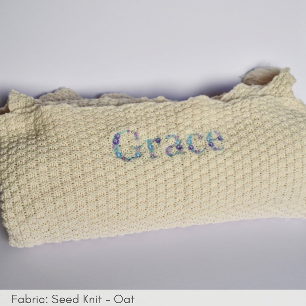Knitted blanket with 'Grace' embroidered on a light gray background