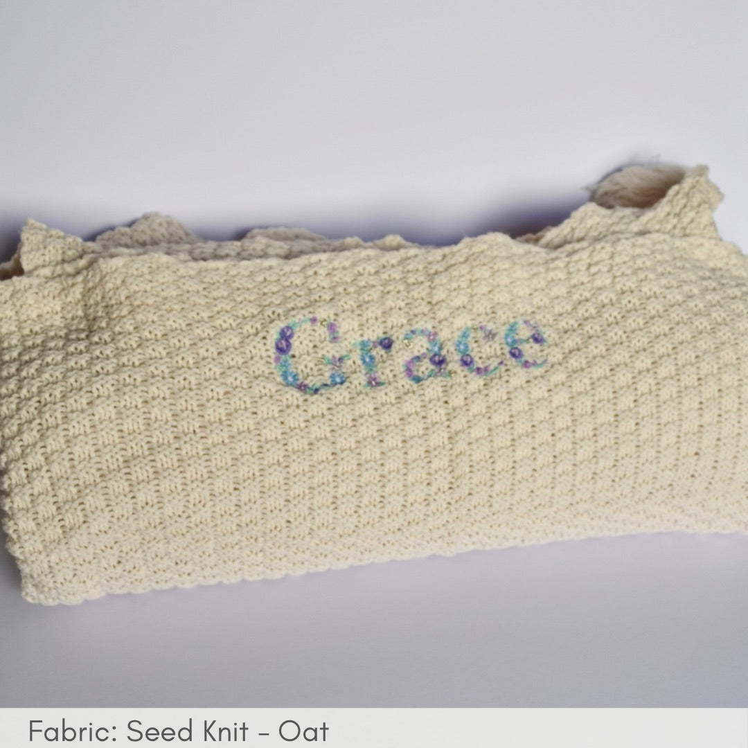 Knitted blanket with 'Grace' embroidered on a light gray background