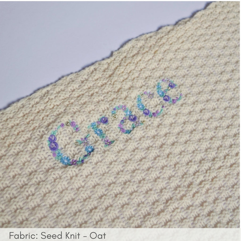 Textile with 'Grace' embroidered in floral pattern on a textured fabric background