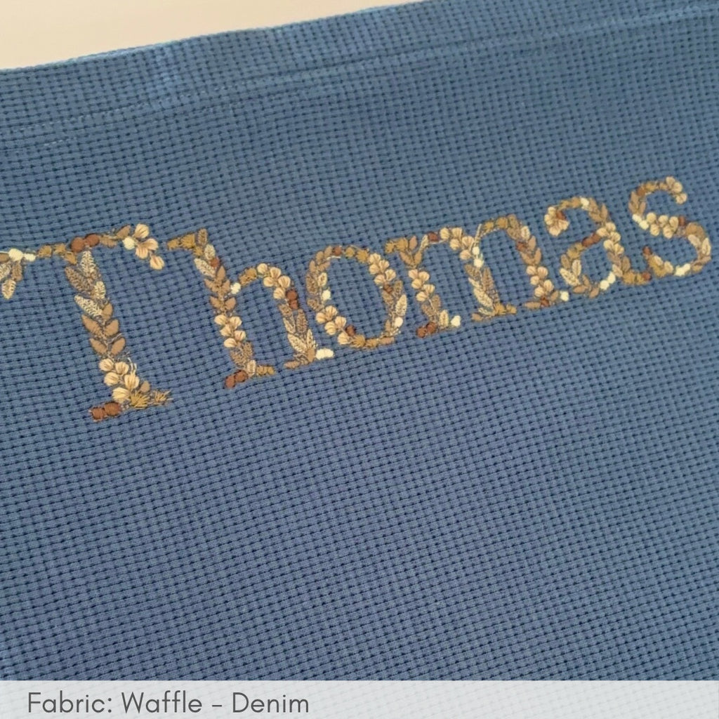 Embroidered name 'Thomas' on a blue fabric background