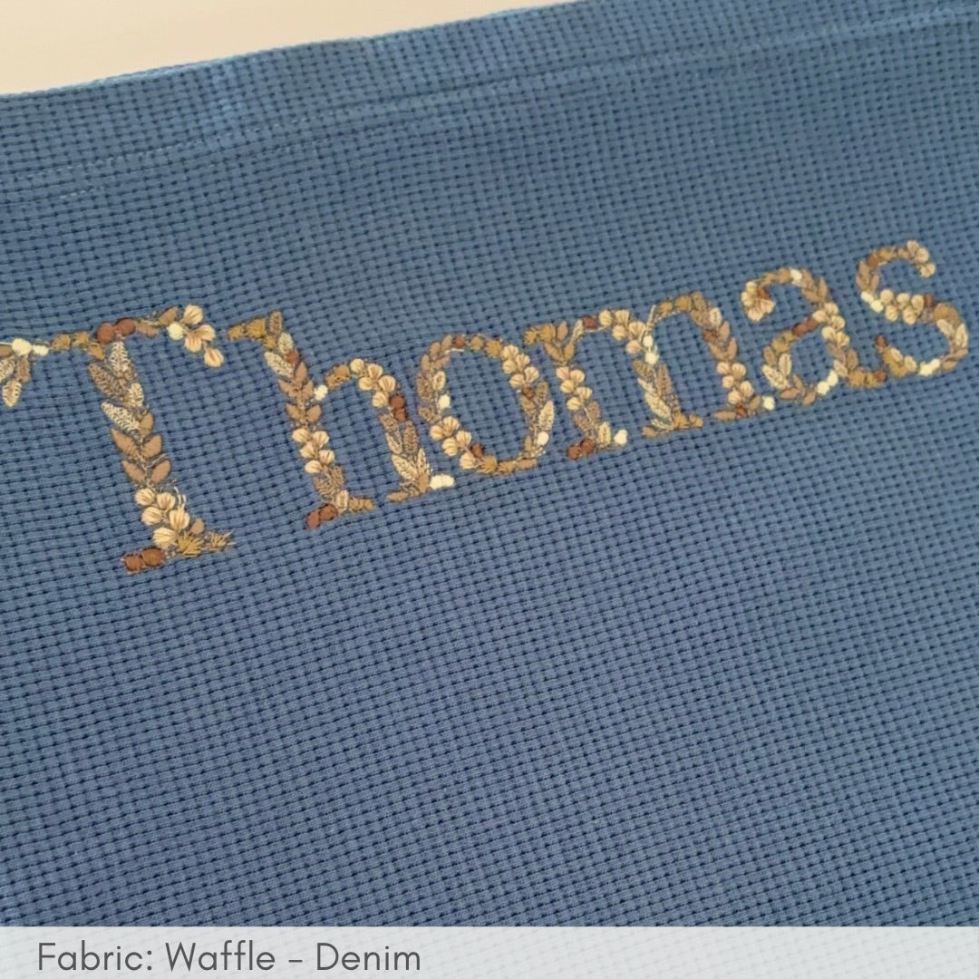 Embroidered name 'Thomas' on a blue fabric background