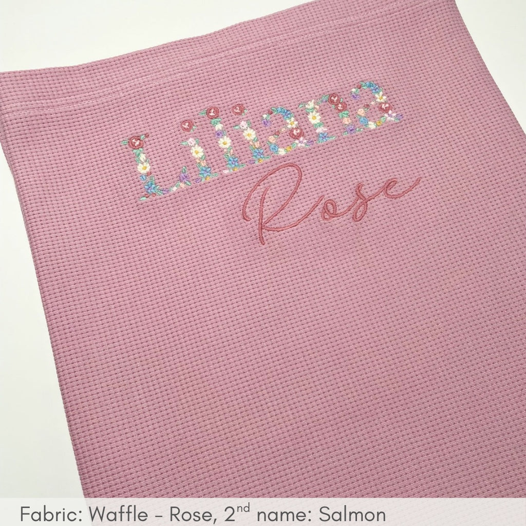 Pink textured blanket with floral and script text on a white background