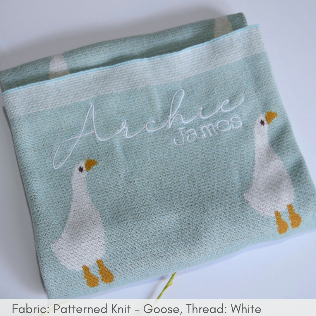 Knitted blanket with goose and embroidered names on a white background